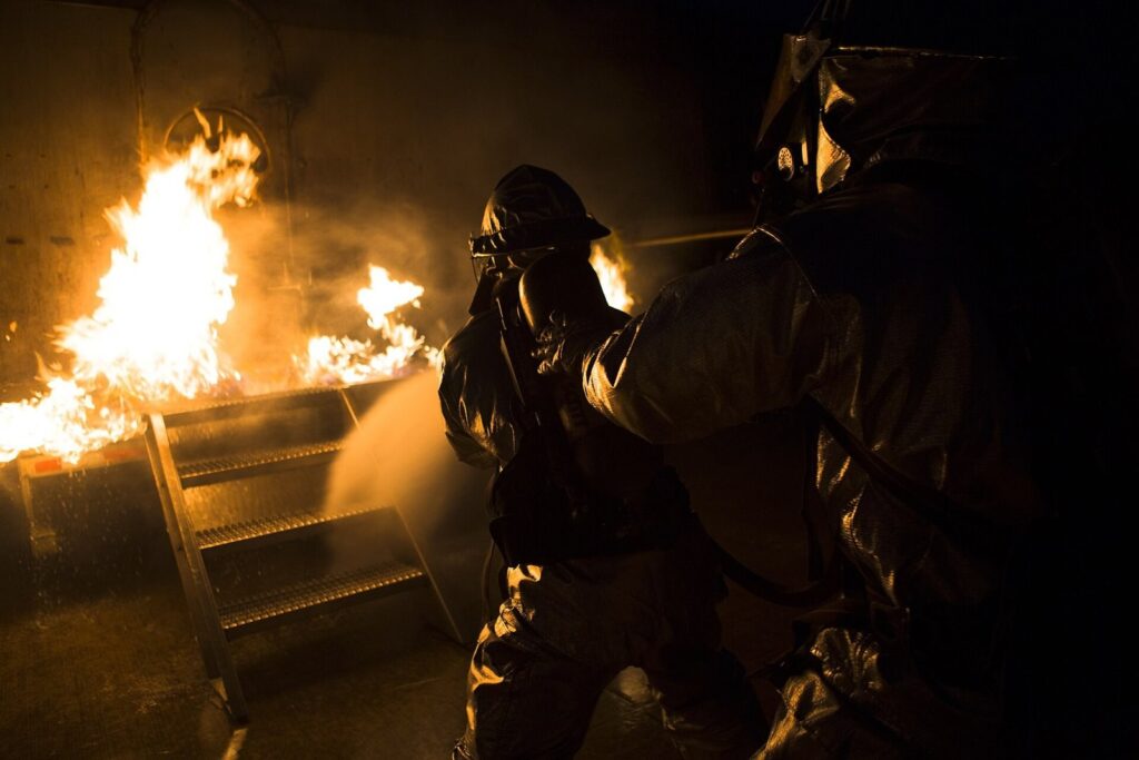 Firefighter spraying a hose inside a fire training bay